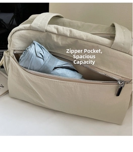 Close-up of a beige nylon tote bag featuring a front zipper pocket with a folding umbrella