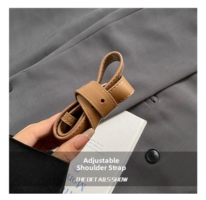 Close-up of brown leather adjustable shoulder strap with detailed stitching on buckle