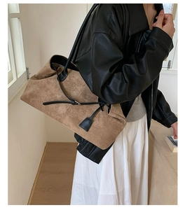Dettaglio di una grande borsa tote in pelle scamosciata marrone con cinturini in pelle nera