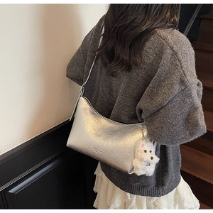 Detailed texture of silver metallic crinkled leather shoulder bag with plush dog charm