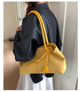 Vista laterale di una borsa tote in pelle scamosciata gialla e giacca di pelle