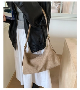 Close-up of a camel suede crossbody bag shown on a model in a minimalist vintage style