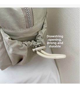 Close-up of khaki nylon shoulder bag showing drawstring design and silver metal zipper