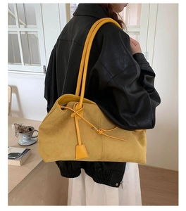 Dettaglio della borsa tote in pelle scamosciata gialla con nodo e ciondolo quadrato