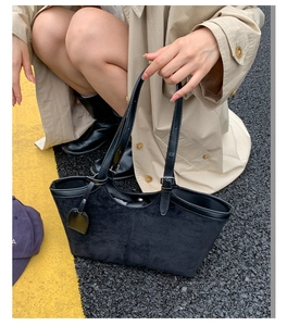 Close-up of black suede tote bag with leather trim and adjustable silver buckle strap