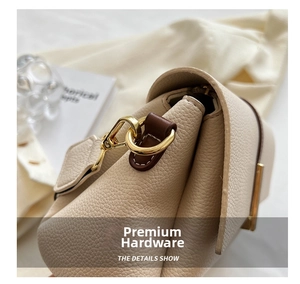 Detail of lychee pattern leather and glossy gold hardware on the beige crossbody bag