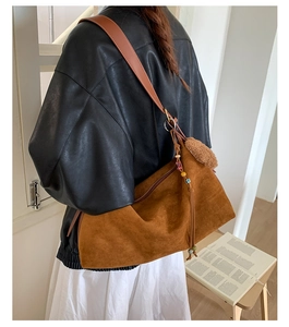 Brown faux suede crossbody bag with vintage tassel charms and long leather strap shown on model