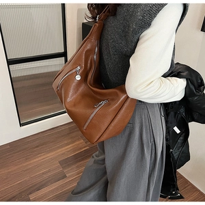 Detail of vintage brown PU leather hobo bag with dual metallic zippers on a model