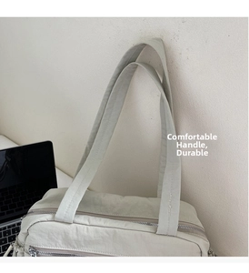 Detail of durable handles and smooth metal zipper on this nylon tote commuter bag