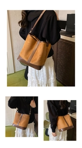 Close-up of brown frosted leather bucket bag featuring dark contrast piping and gold hardware