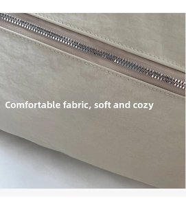 Detailed macro view of the cream-colored textured fabric and smooth metal zipper on bag