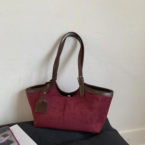 Close-up of burgundy suede tote bag with leather straps and adjustable metal buckle detail