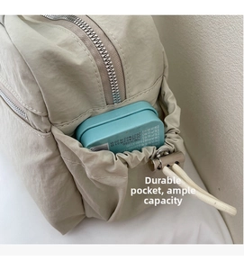 Detail of durable side pocket with drawstring and spacious storage on beige nylon tote bag