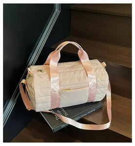 Close-up of pink quilted travel bag with gold zippers placed on a designer book