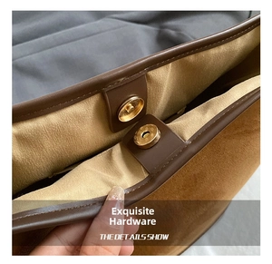 Detail of a gold circular magnetic snap closure on a brown suede bucket handbag
