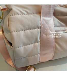 Detail of pink quilted canvas gym bag showing soft fabric texture and gold metal buckle