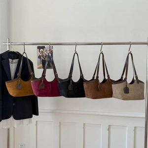 Retro shoulder tote bags in five earthy colors displayed on a minimalist metal rack