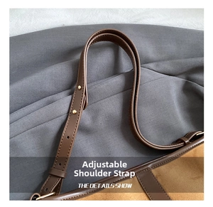 Close-up of adjustable leather shoulder strap with golden metal buckle on brown bucket bag
