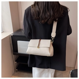 Chic beige pebbled leather shoulder bag with wide strap shown on model's shoulder