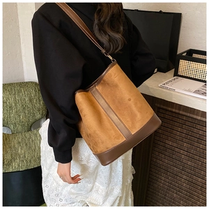 Brown frosted suede bucket bag shown on shoulder with adjustable leather strap detail