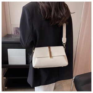 Close-up of creamy beige lychee textured leather shoulder bag with wide strap detail