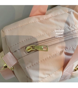 Detailed close-up of smooth gold metal zipper and pink waterproof nylon fabric of sport bag