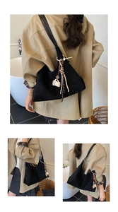 Detail of black suede tote bag featuring bohemian tassel and coffee cup charm