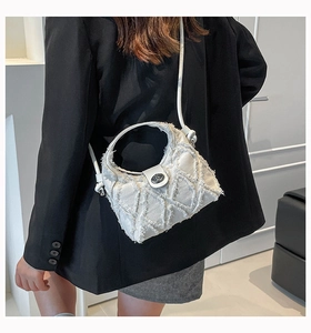 Dettaglio della borsa in tessuto bianco con trama a frange e chiusura a girello