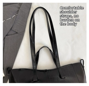 Detail view of double shoulder straps on a black glossy leather tote bag with stitching