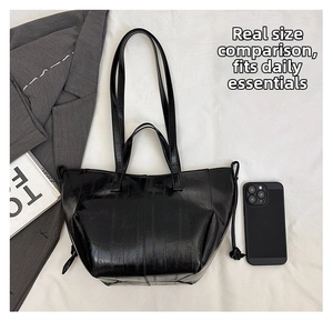 Detailed top view of black glossy tote bag with texture, showing size with a smartphone