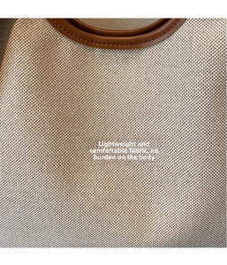 Détail du tissu tissé blanc cassé et de la poignée en cuir marron d'un sac cabas