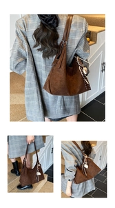 Detail view of large brown suede tote bag with leather strap and striped scarf charm