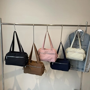Multiple colors of versatile nylon shoulder bags featuring silver zipper pockets on display