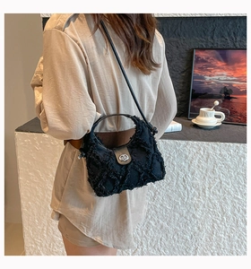 Dettaglio della borsa in denim nero con frange sfilacciate e chiusura a girello in metallo