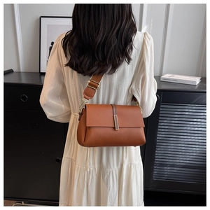 Close-up of brown litchi pattern leather bag with wide strap on model's shoulder