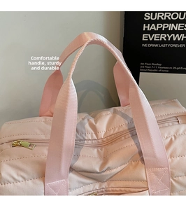 Detail of pink quilted gym bag featuring reinforced handles and premium gold zipper hardware