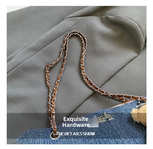 Detail view of denim tote bag with silver metal lock, chain strap, and plush bear charm