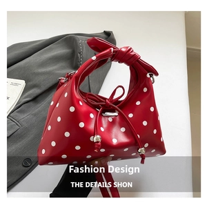 Macro view of a red polka dot leather handbag featuring a knotted handle and bow detail
