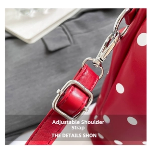 Detail of adjustable red polka dot leather strap with silver metal buckle and spring hook