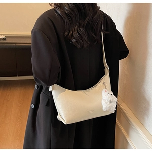 Detail of cream white pleated leather shoulder bag with a cute plush animal charm