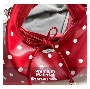 Detail of red polka dot handbag featuring a decorative bow and silver metal logo plate