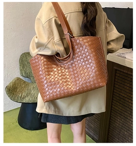 Brown woven tote bag with Intrecciato pattern shown from back view on model's shoulder