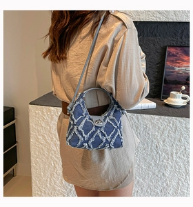 Dettaglio borsa a tracolla in denim blu con cuciture bianche e fibbia in metallo argento