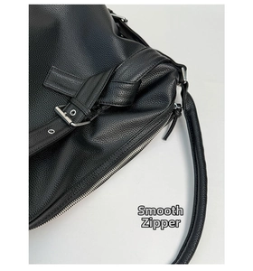 Close-up of black lychee grain leather tote bag featuring smooth silver metal zippers