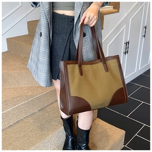Détail d'un grand sac cabas en toile avec garnitures et poignées en cuir marron en intérieur