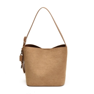 Minimalist brown suede bucket bag with wide strap and matching leather decorative tag