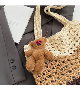 Detail of hand-woven tote bag with a brown plush teddy bear charm and cute sunglasses