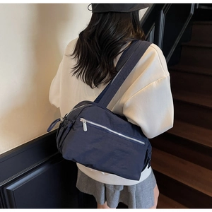 Detail of navy blue large capacity nylon tote bag with multiple pockets on model's back