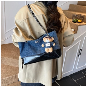 Detail of color-block tote bag with chain strap and teddy bear charm on model