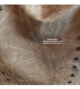 Detail of beige tote bag fabric with industrial metal rivets and twill texture